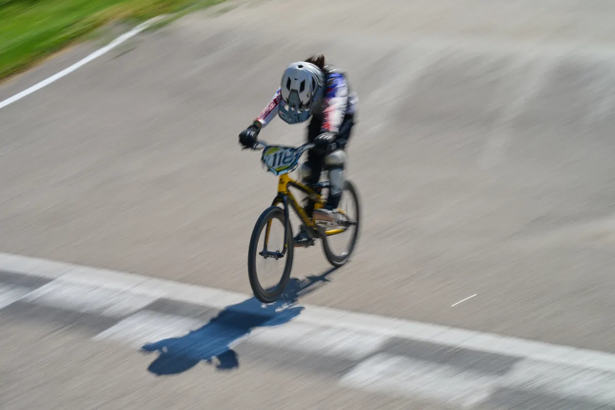 A young XKIDS BMX rider going down a track during a race-day session.