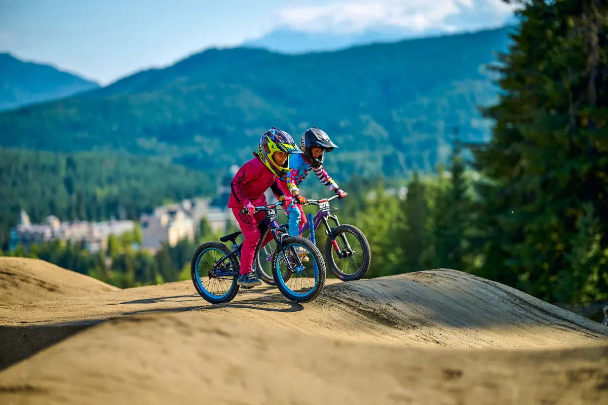 Young XKIDS riders on mountain bikes at a destination trail venue.